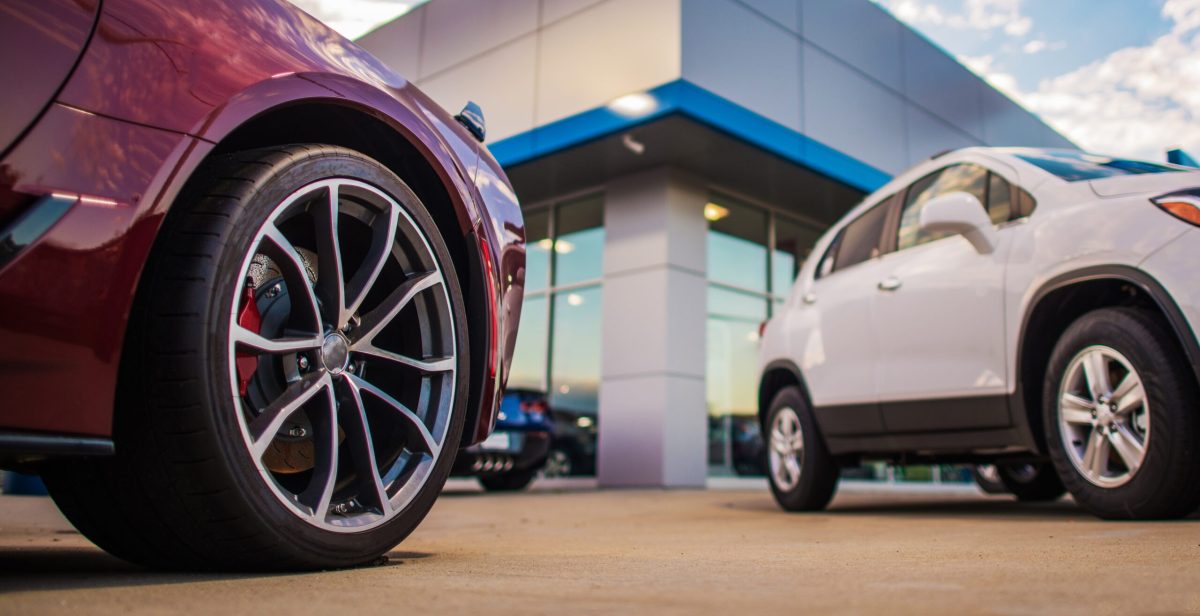 Automotive Dealership Store. New and Pre Owned Vehicles in Front of the Showroom Building.
